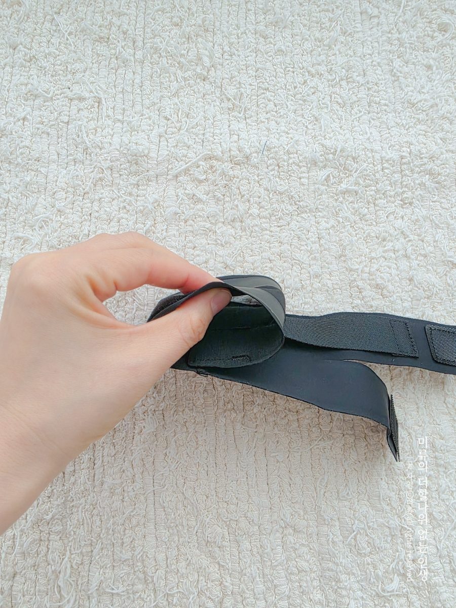 한 손으로 스트랩을 당겨 조이는 모습