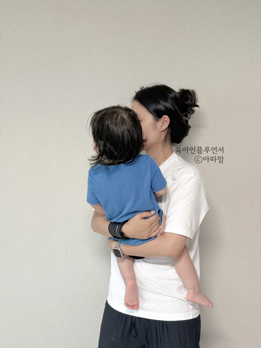 아기를 안은 뒷모습, 손목에 보호대를 착용한 상태
